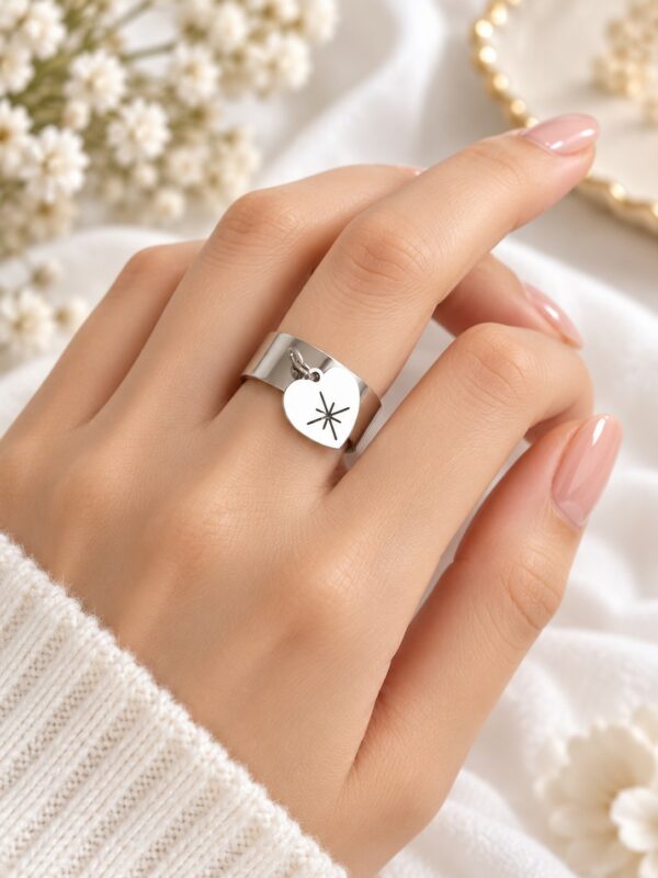 Bague Amour cœur argentée ajustable en acier inoxydable portée au doigt.