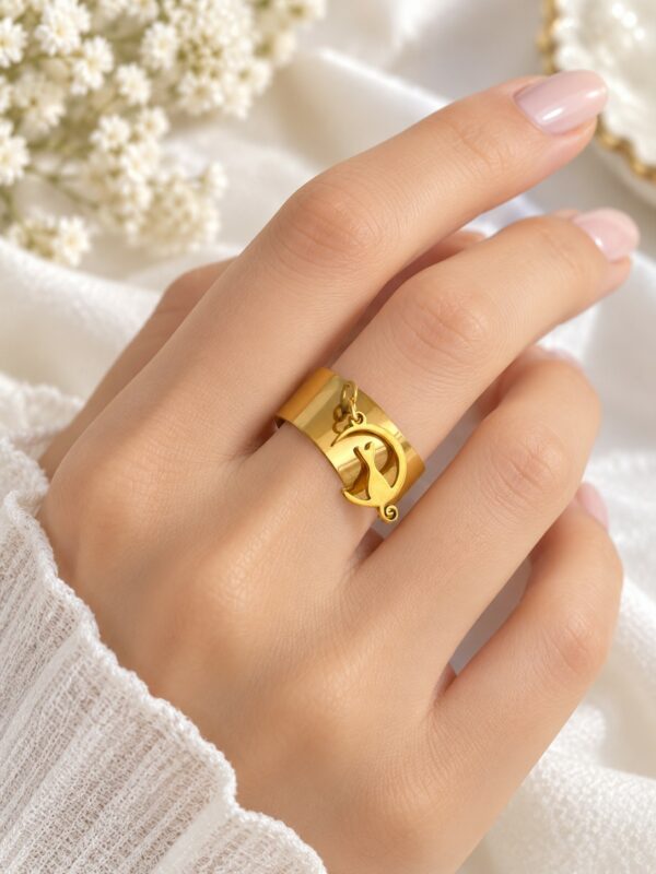 Bague Cathie chat dorée ajustable en acier inoxydable portée au doigt.