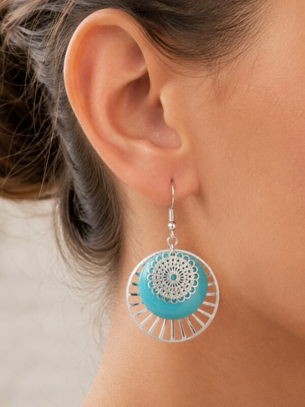 Boucles d'oreilles pendantes argentées et bleues Ariana portées sur une oreille.