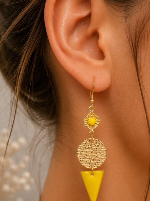 Boucles d'oreilles Flavie pendantes dorées et jaunes portées sur une oreille.