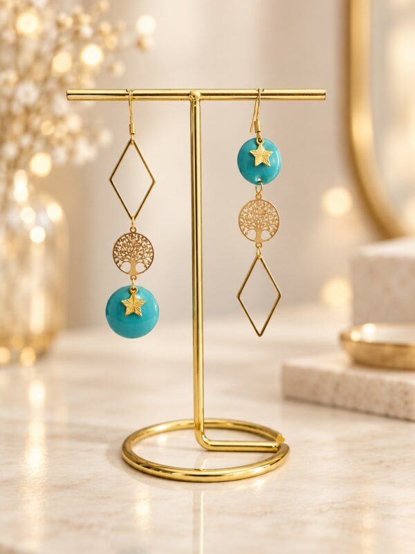 Boucles d'oreilles Helga asymétriques dorées et bleues présentées sur support.