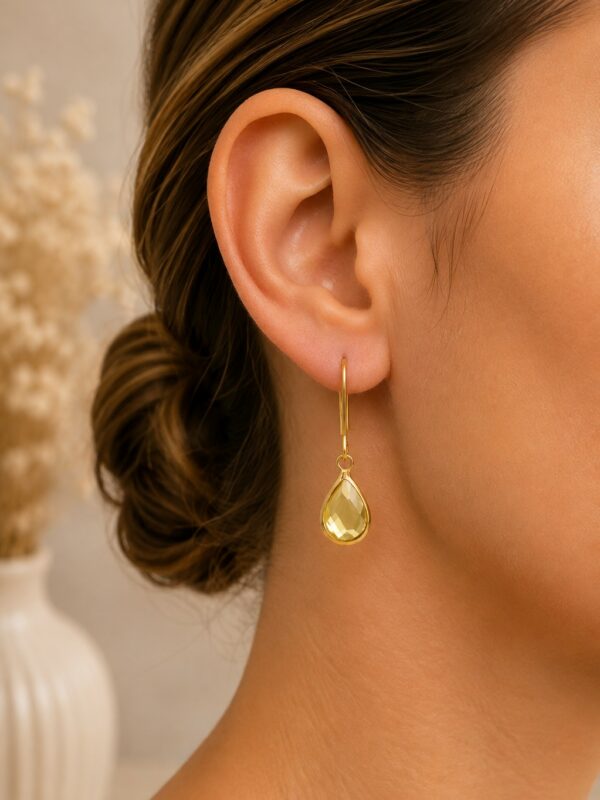 Boucles d'oreilles goutte jaune dorées Lili jaune portées sur une oreille.