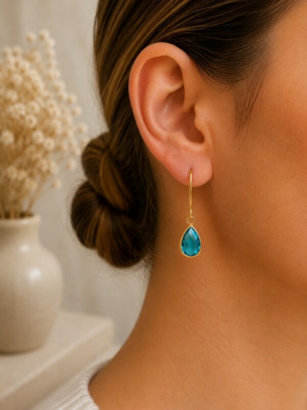 Boucles d'oreilles dorées perle en verre turquoise Lili portées sur une oreille.