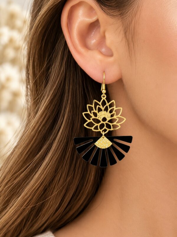 Boucles d'oreilles Ludivine dorées et noires portées sur une oreille.