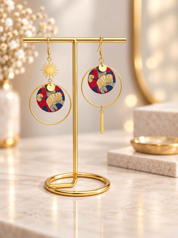 Boucles d'oreilles Nina asymétriques dorées et multicolores présentées sur support.