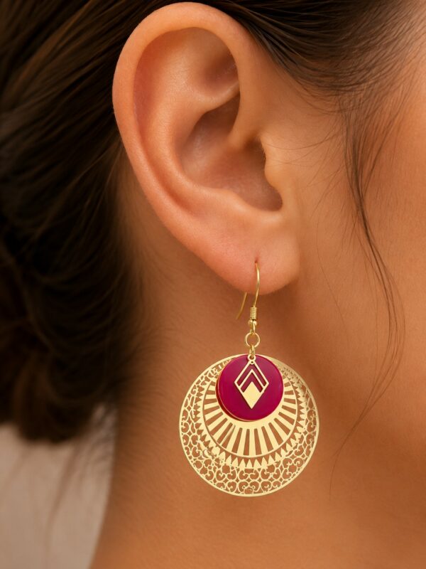Boucles d'oreilles Framboise pendantes dorées et framboise portées sur une oreille.
