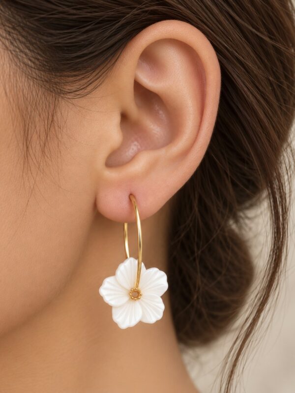 Créoles Chloé dorées avec fleur en perles d'eau douce portées sur une oreille.