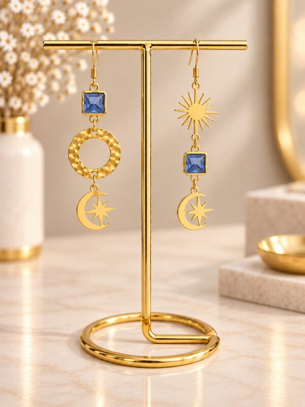 Boucles d'oreilles Elodie asymétriques dorées et bleues présentées sur support.