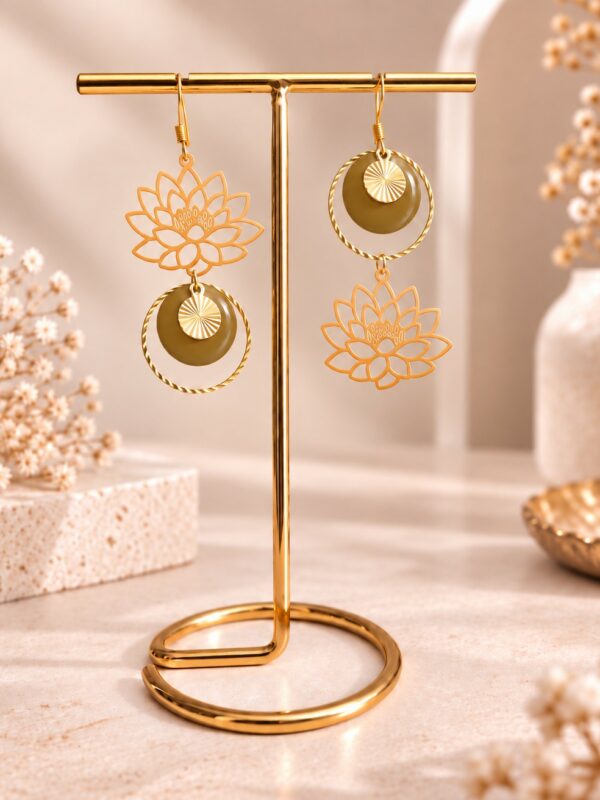 Boucles d'oreilles Sérénity asymétriques dorées et kaki brun avec motif lotus sur support.