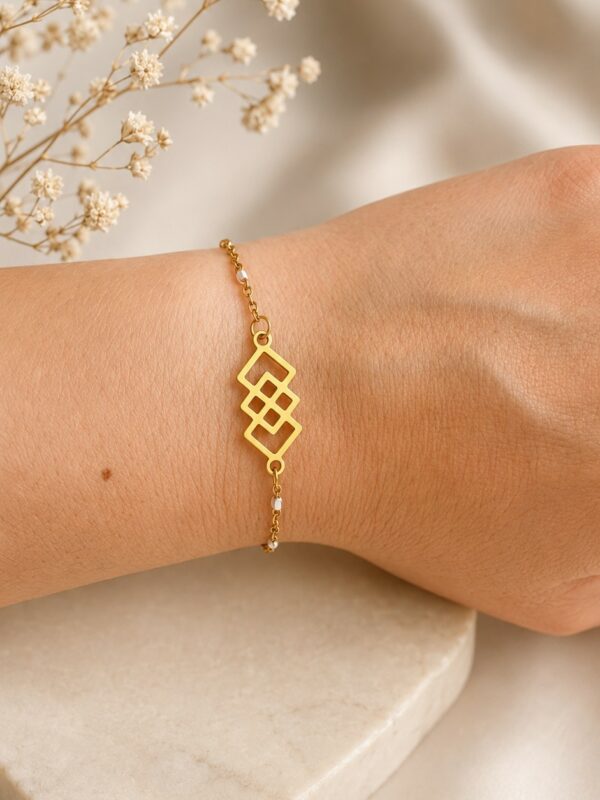 Bracelet doré et blanc en acier inoxydable porté au poignet avec motif géométrique doré et perles blanches - bracelet Alizée