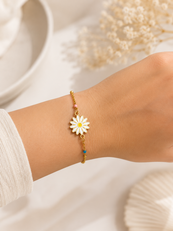 Bracelet doré et fleur blanche en acier inoxydable porté au poignet.