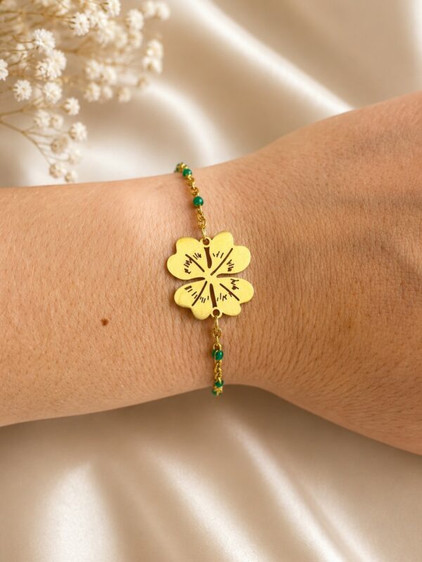 Bracelet doré vert en acier inoxydable avec trèfle à quatre feuilles porté au poignet
