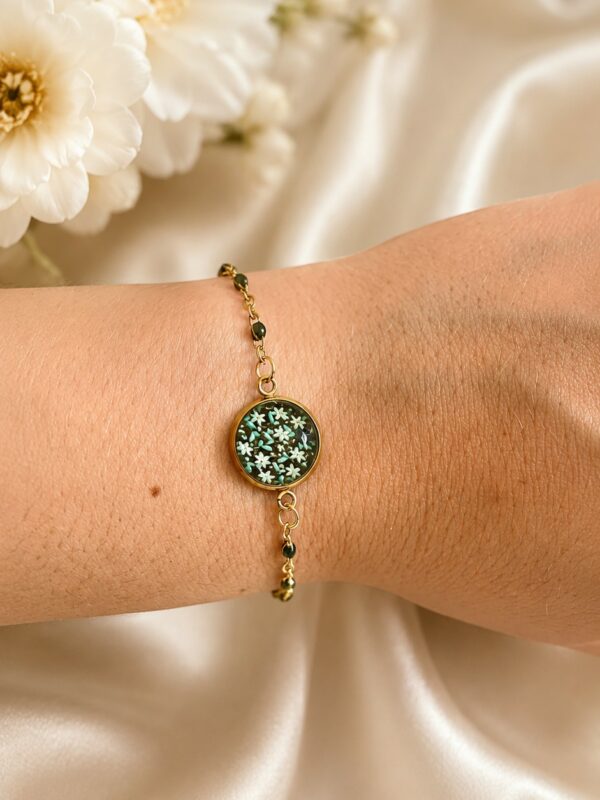 Bracelet doré noir en acier inoxydable avec médaillon fleuri porté au poignet