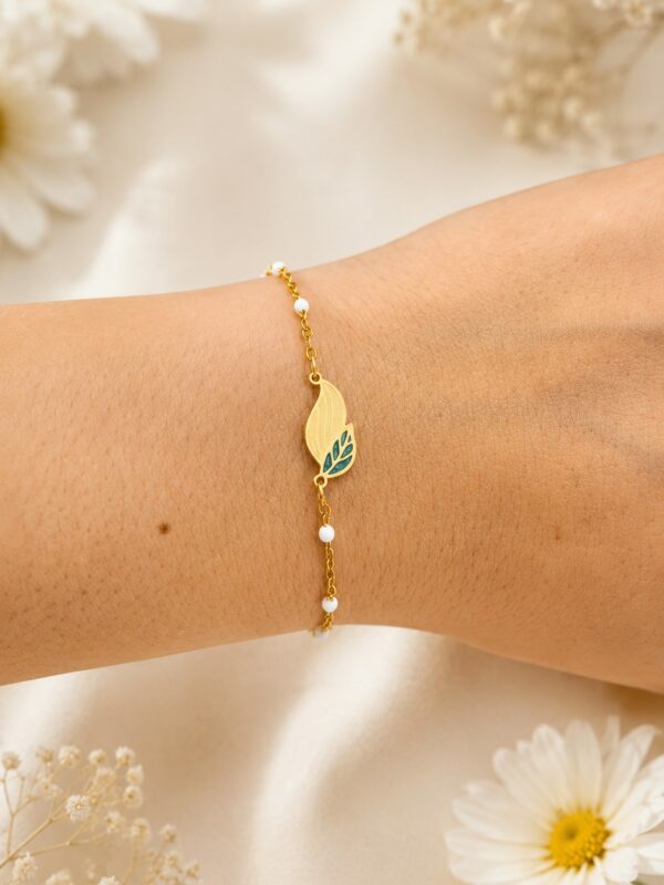 Bracelet doré blanc en acier inoxydable avec motif feuille porté au poignet