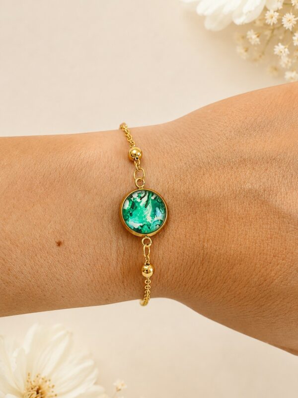 Bracelet doré et vert en acier inoxydable avec médaillon abstrait et perles multicolores porté au poignet