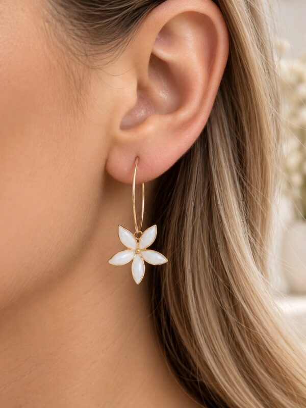 Créoles Alice dorées et blanches motif fleur portées sur une oreille.