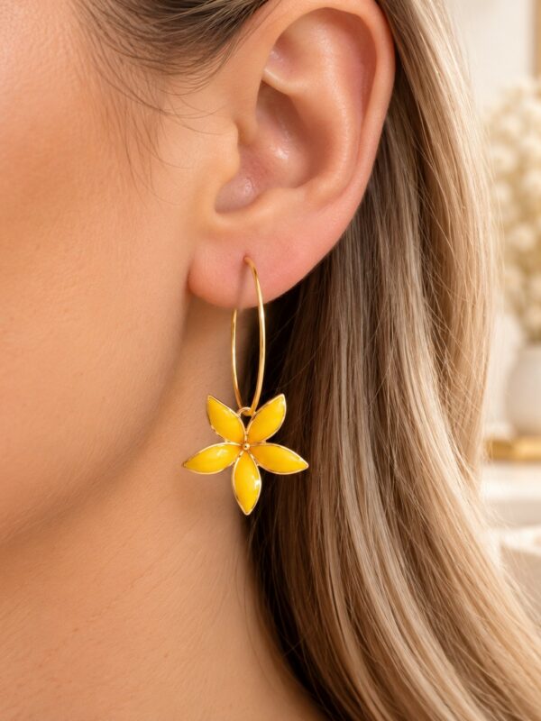Créoles Alice dorées et jaunes motif fleur portées sur une oreille.