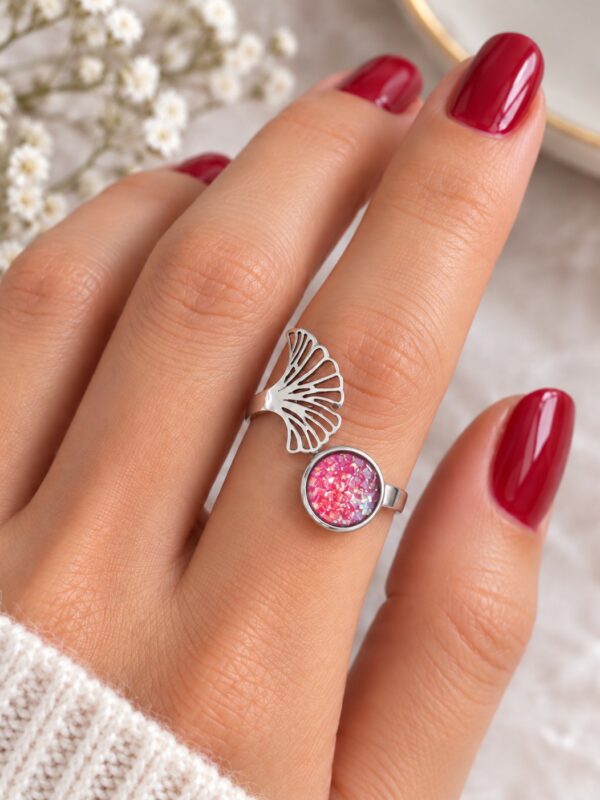 Bague Ginkgo argentée ajustable avec résine rose pailletée portée au doigt.