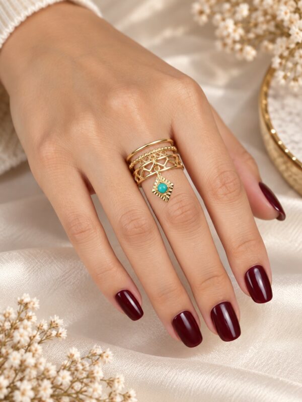 Bague Irina Turquoise dorée ajustable avec losange turquoise portée au doigt.