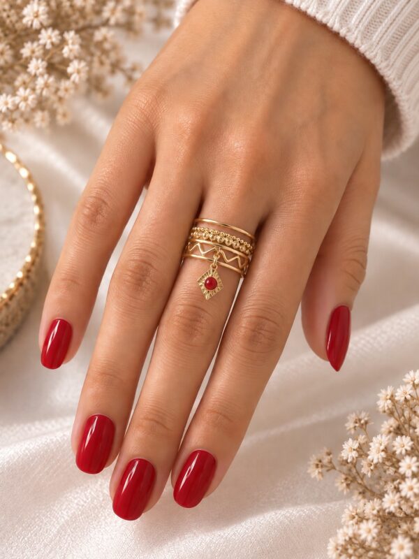 Bague Irina Rouge dorée ajustable avec losange rouge portée au doigt.