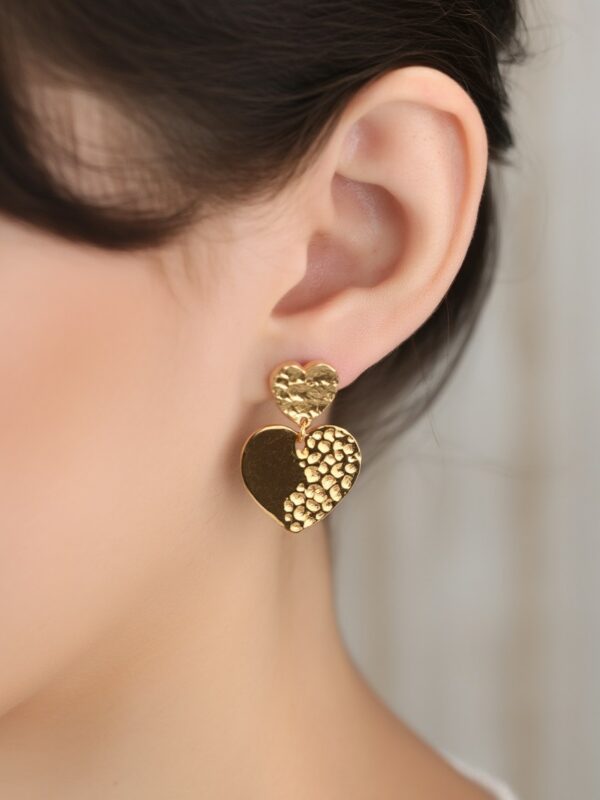 Boucles d'oreilles dorées cœur en acier inoxydable Amour portées sur une oreille.