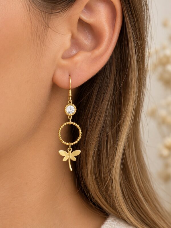 Boucles d'oreilles Louise dorées libellule en acier inoxydable portées sur une oreille.