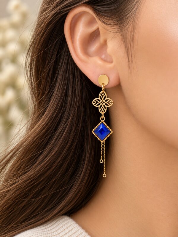 Boucles d'oreilles Lucille dorées et bleu roi portées sur une oreille.