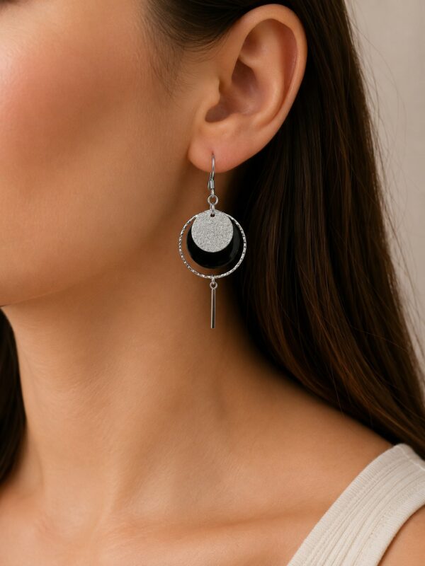 Boucles d'oreilles Juliette pendantes argentées et noires portées sur une oreille.