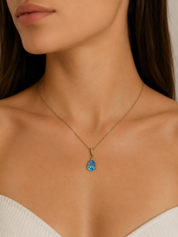 Collier doré goutte turquoise en acier inoxydable porté au cou.